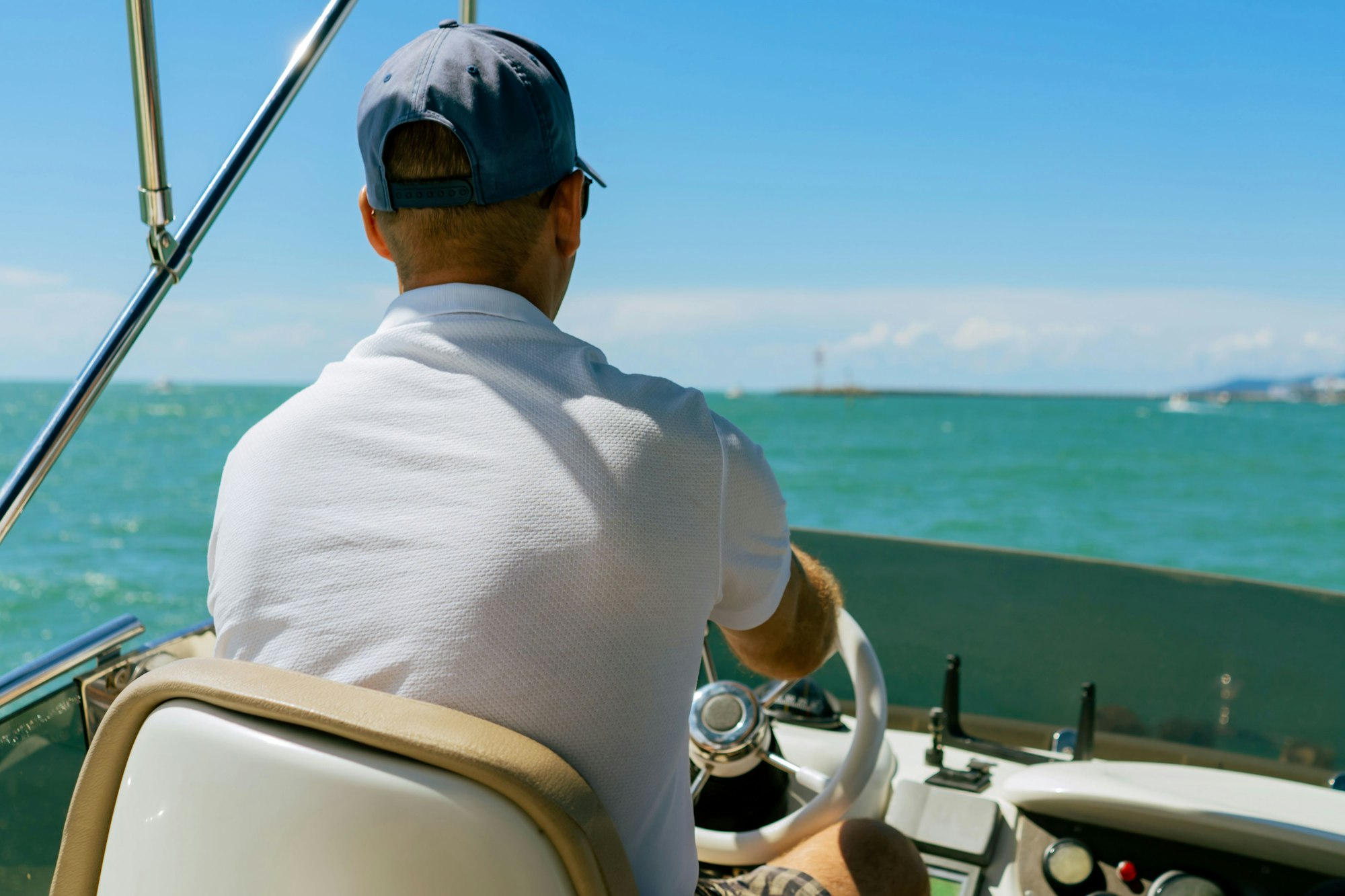 Bach view of middle-aged man driving luxury motor yacht. Captain at the helm of motor boat.